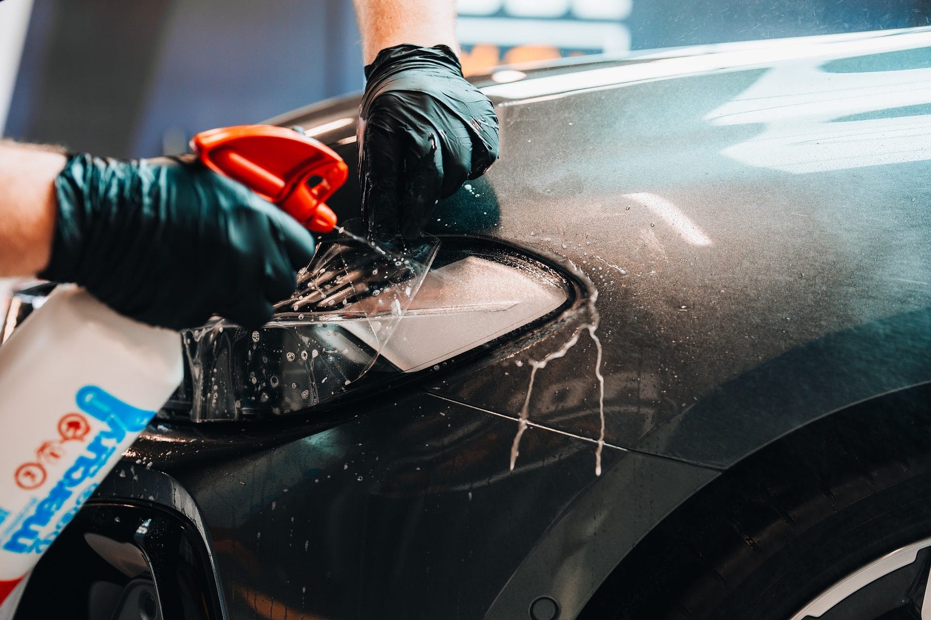 Gloved hand applying PPF film to a car panel